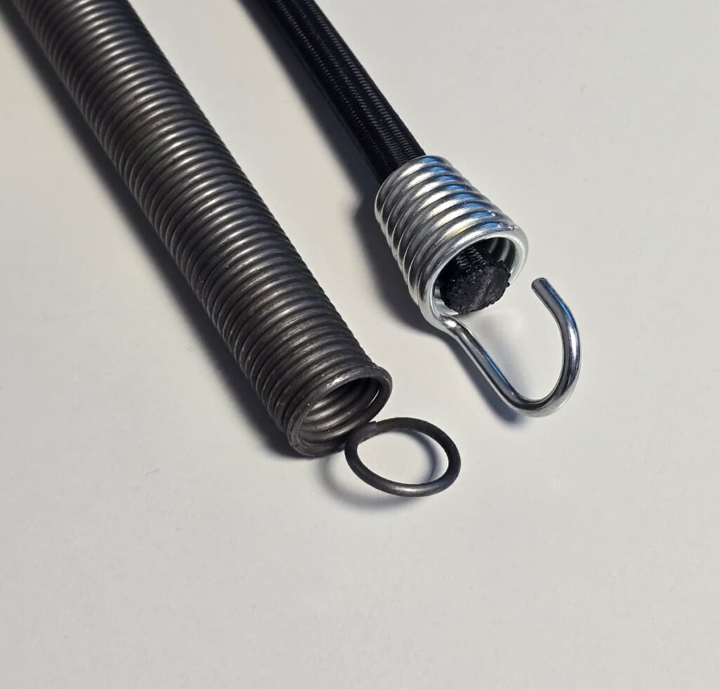 Vergleich zwischen Gummiseil und Metallfeder – elastisches Gummiseil mit Haken neben Stahlfeder zur Gegenüberstellung unterschiedlicher Spannsysteme.